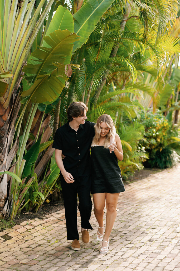 couple walking on path for their downtown naples beach engagement session