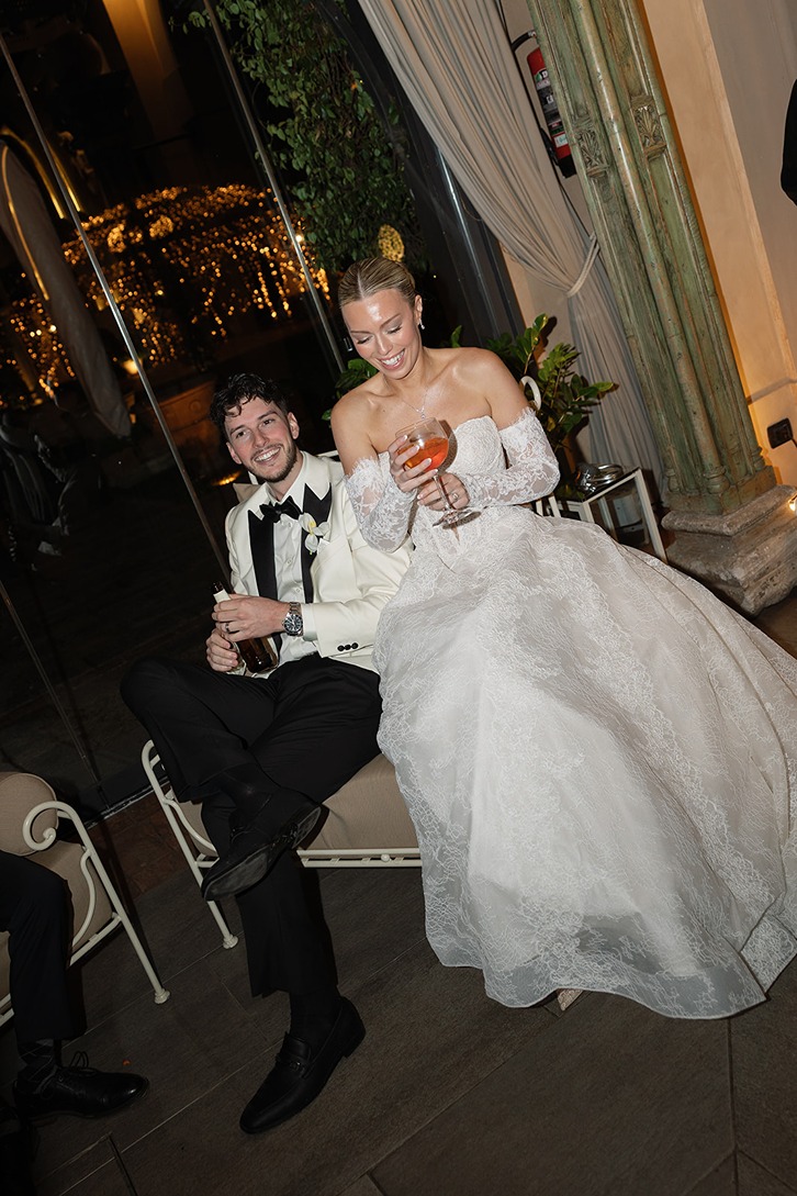 the bride and groom sitting on a bench captured by a italy wedding videographer and photographer